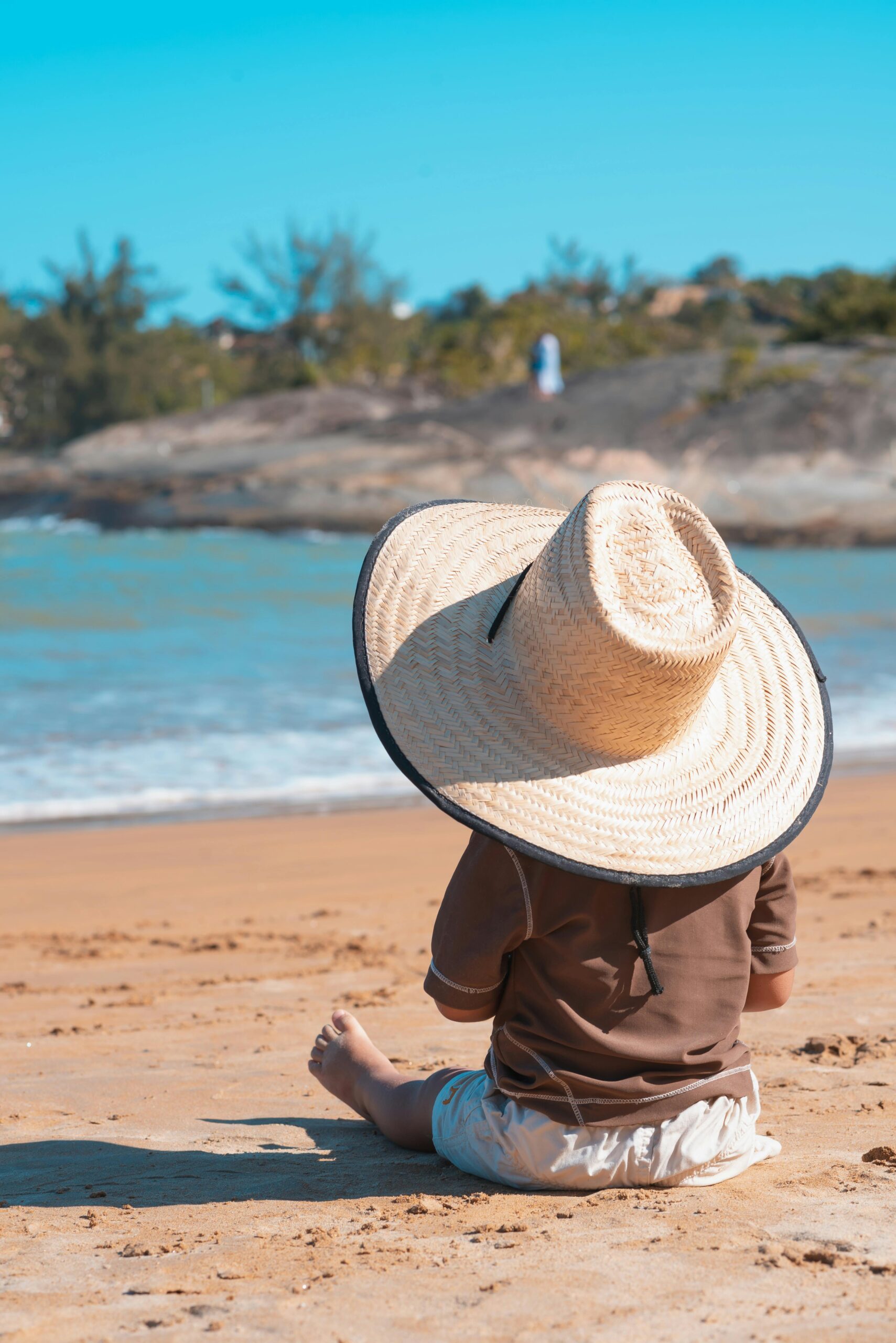 little kid on beach wearing hat